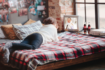 Anonymous woman watching TV on bed