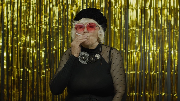 Elderly Style Mature Woman in Fashion Black Clothes in Sunglasses Posing, Smoke Cigarette