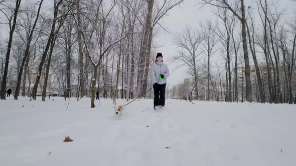 Happy Girl with Dog Running Along in Park Winter