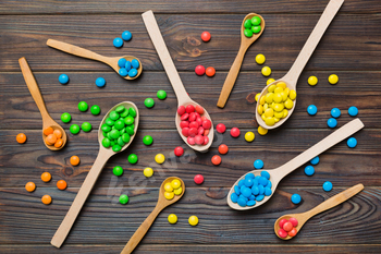 delicious colorful sweet candies on spoon on colored background .