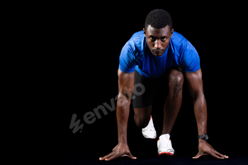 African American man in starting position for a sprint, with copy space on a black background