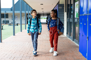 Biracial boy and girl walk past lockers at school