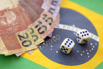 Dice cubes with brazilian money bills on flag of Brasil Republic