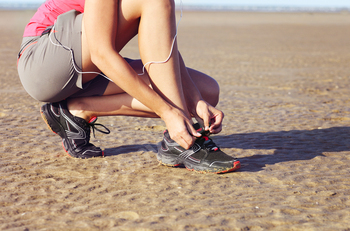 Young woman runner tying shoelaces