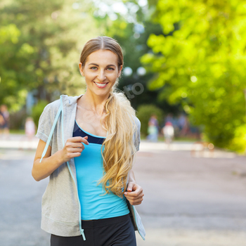 Young female runner in hoody is jogging in the city