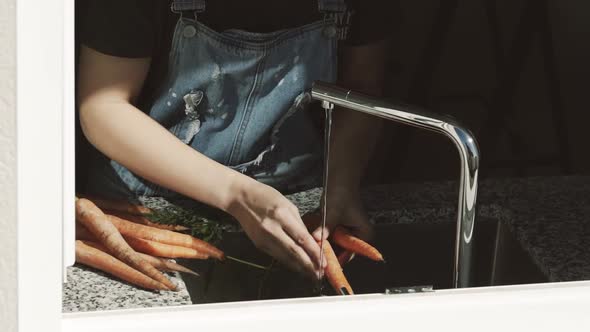 Crop woman hands washing carrot