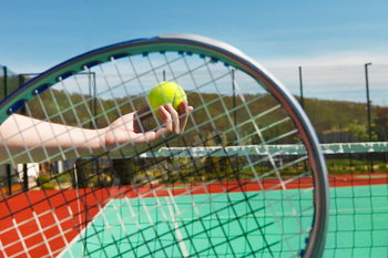 Tennis player prepares to serve a tennis ball