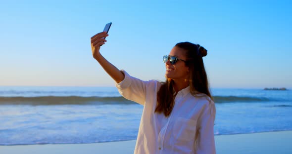 Woman taking selfie with mobile phone in the beach