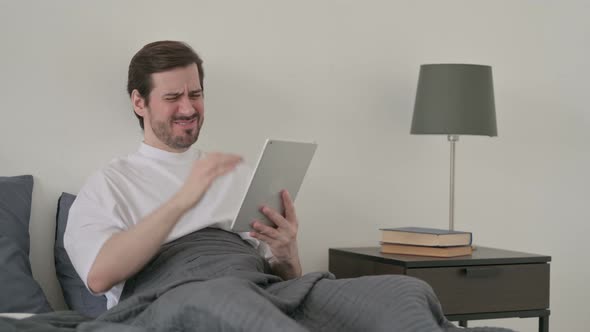 Young Man Reacting to Loss on Tablet in Bed