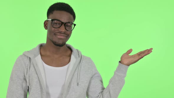 African Man Showing Product in Hand on Green Background