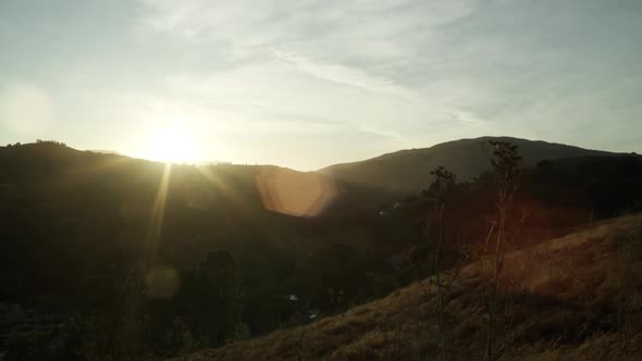 The camera cranes down on a Northern California hillside as the sun sets in the distance.