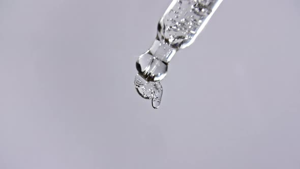 Cosmetic Pipette with Drops of Oil Close Up on Gray Background