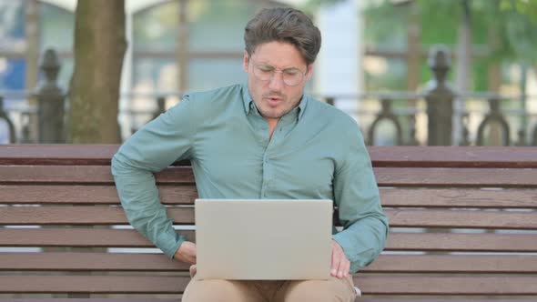 Man having Back Pain while using Laptop, Outdoor