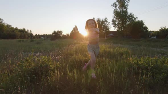 Girl Runs Across the Field Towards the Setting Sun