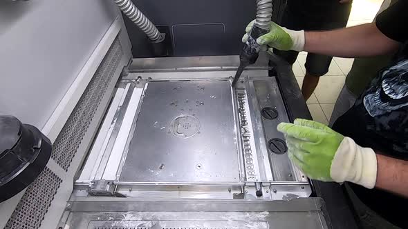 A Male Worker Cleans the Surface of an Industrial 3D Printer From White Powder
