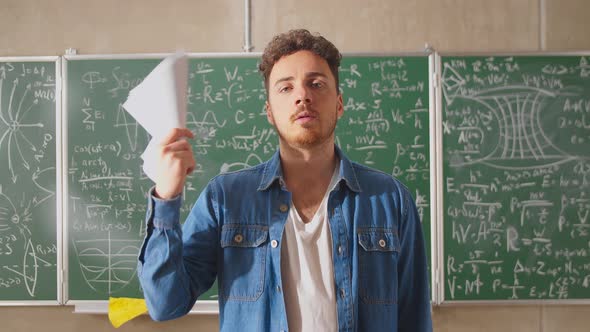 Young Teacher Fanning Paper Sheets in a Very Hot Classroom