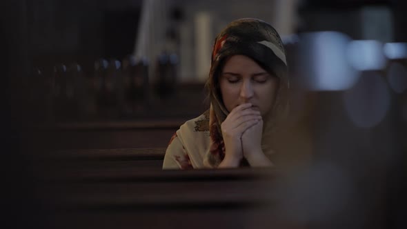 Woman in headscarf praying in church