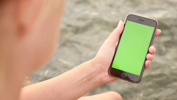 NICE, FRANCE - JULY 2017 Slow motion of female with green screen display modern phone by the sea