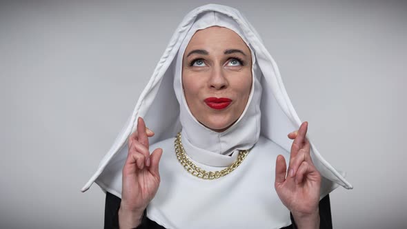 Smiling Woman in Nun Costume Crossing Fingers in Hope Gesture Looking Up Wishing Praying