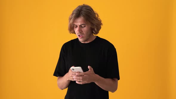 Displeased blond man texting by phone