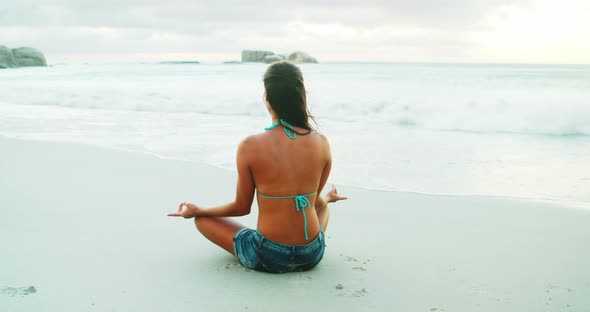 Woman performing yoga on beach