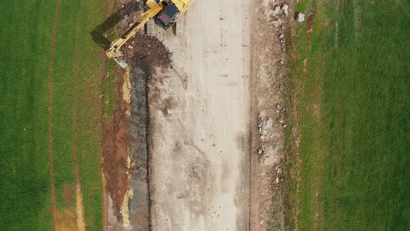 Aerial View of Excavator Collects Soil From the Green Field