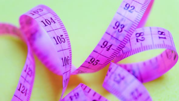 Close Up of a Violet Measure Tape on Yellow Rotating Background