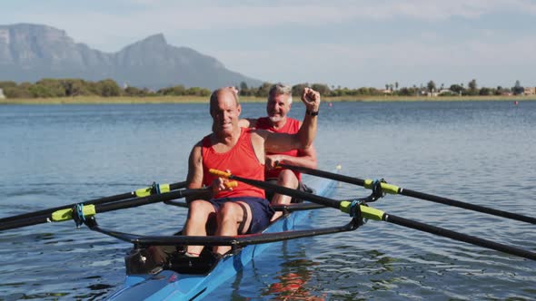 Two senior caucasian men in rowing boat raising hands and cheering