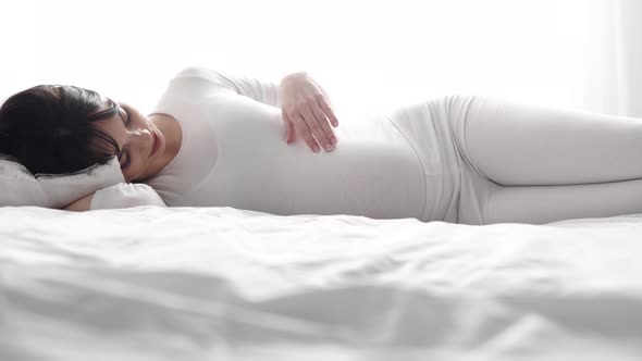 Pregnancy. Beautiful Woman Lying On Bed And Touching Baby Belly