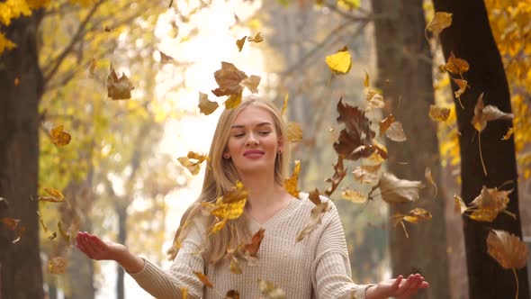 Happy woman in autumn park drop up leaves