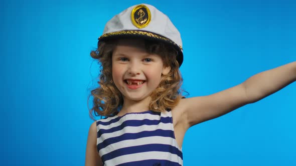 Little Cute Curly Sailor Girl Puts Her Hand to the Cap and Smiles