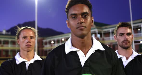 Male rugby players with rugby ball and arms crossed standing in stadium 4k