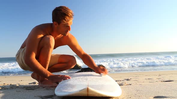 A surfer waxing board before surfing