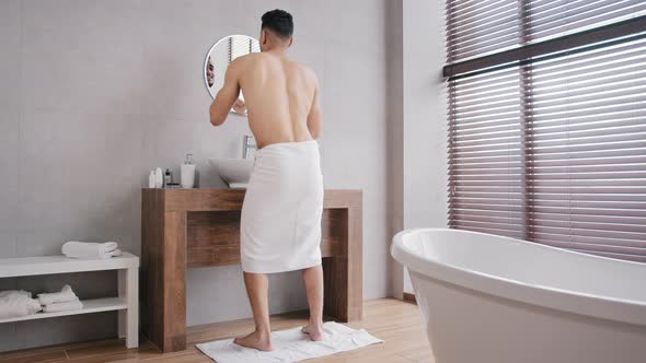 Full Length View Funny Cheerful Man with White Bath Towels Wrapped Around Hips Standing in Bathroom