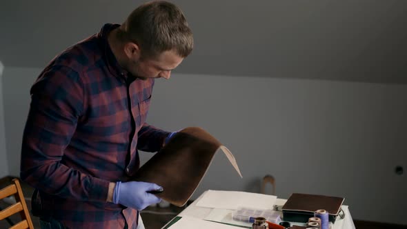 The Process of Manufacturing a Leather Wallet Handmade. The Master Examines a Piece of Painted