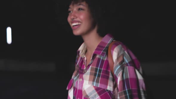 Smiling young woman dancing outdoors at night