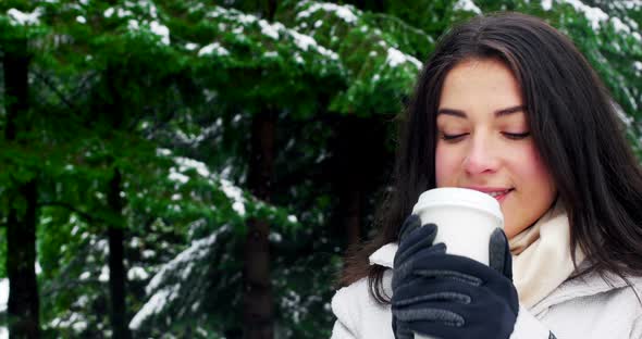 Woman in warm clothing having coffee during snowfall