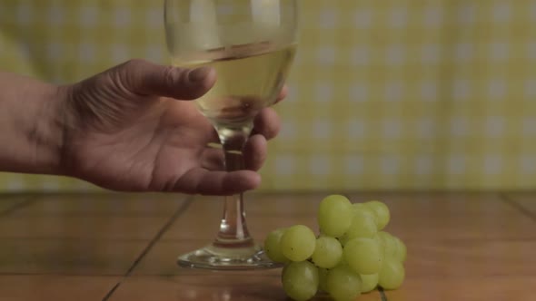 Hand with glass of white wine and grapes close up shot