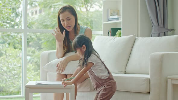 Young mother cheer up to lovely daughter to drawing