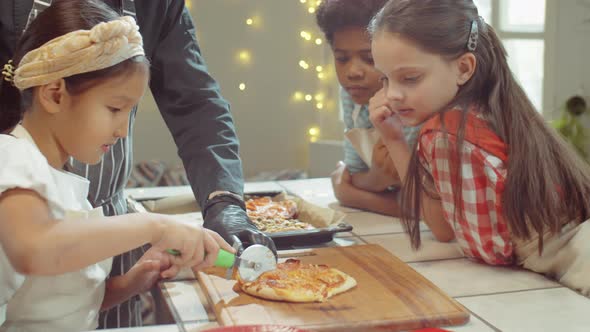 Little Asian Girl Cutting Pizza on Cooking Masterclass