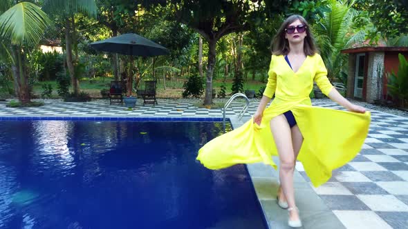 Asian Woman in Yellow Walks Along the Pool