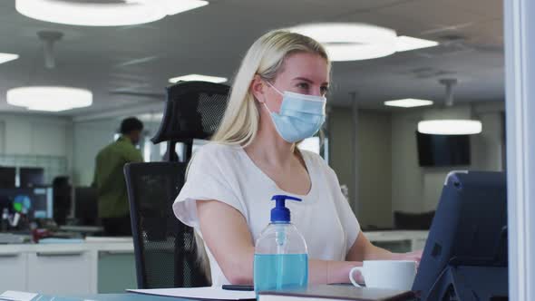 Woman wearing face mask using computer at office