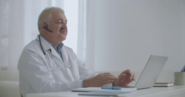 Physician Is Consulting Online, Sitting in Office of Private Clinic, Using Laptop for Talking with