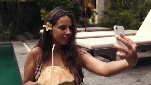 A Beautiful Woman Is Relaxing By the Pool at a Luxury Beach Resort Spa Hotel Taking a Selfie on Her