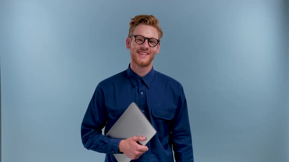 Portrait of Smiling Young IT Specialist with Laptop in Blue Studio