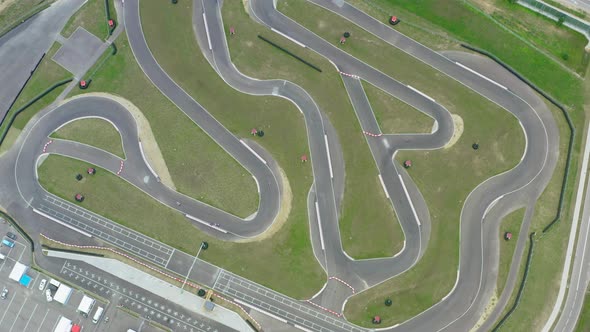 Aerial Top Down View Drone Flies Over Racing Cars Driving on Winding Race Track. Cloudy Summer Day