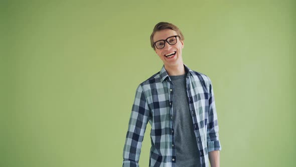 Portrait of Joyful Guy Turning To Camera and Laughing on Green Background