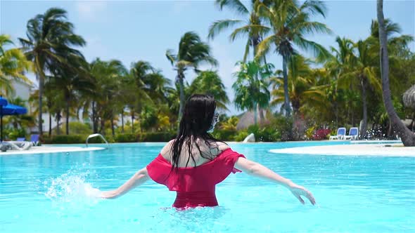 Beautiful Young Woman Relaxing in Swimming Pool. Happy Girl in Outdoor Pool at Luxury Hotel