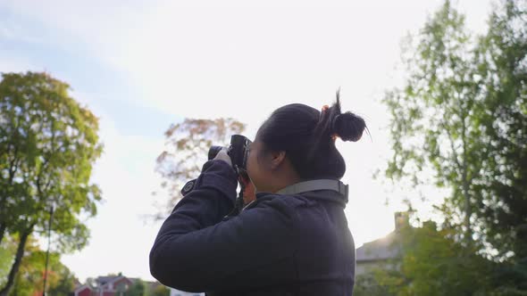 Asian woman standing and taking a picture by camera outside