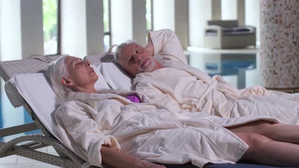 Old Couple Talking While Lying on Sunbeds in Hotel